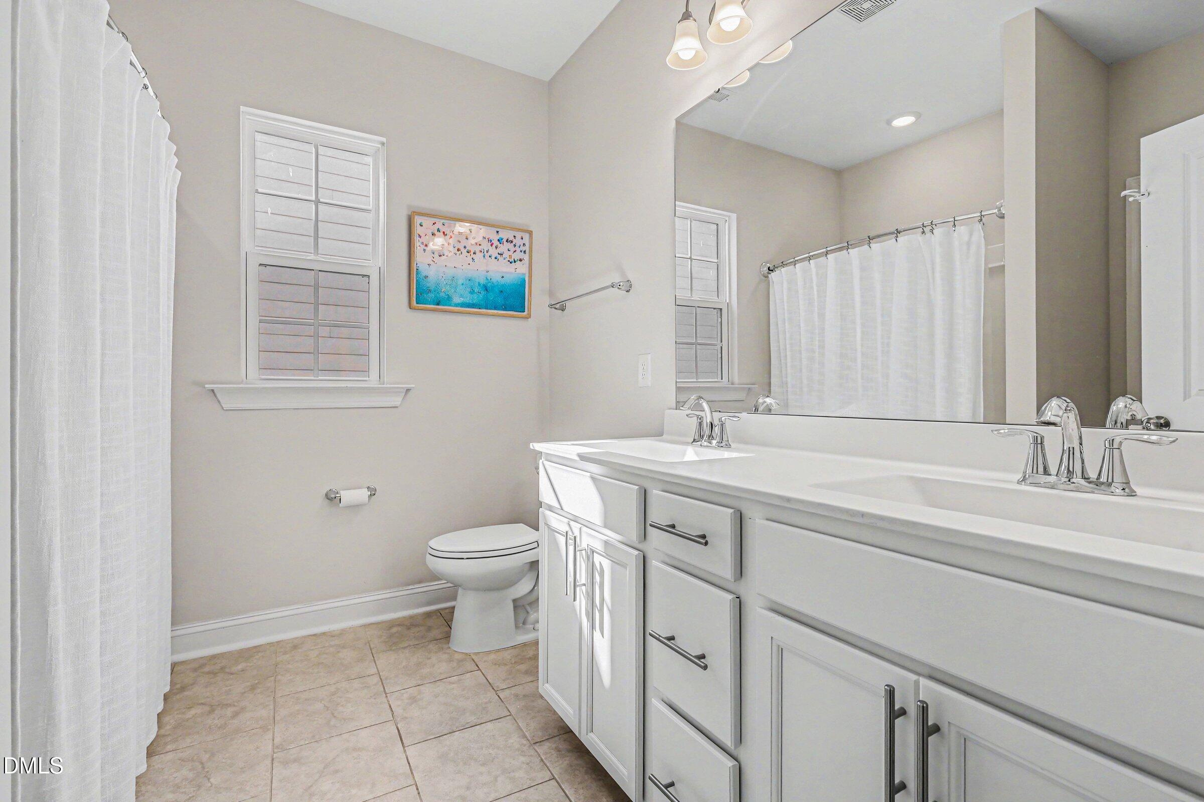 4921 Abundance Avenue Raleigh, NC 27616 - Photo 28 of 36 a bathroom with a double vanity sink a toilet and a mirror