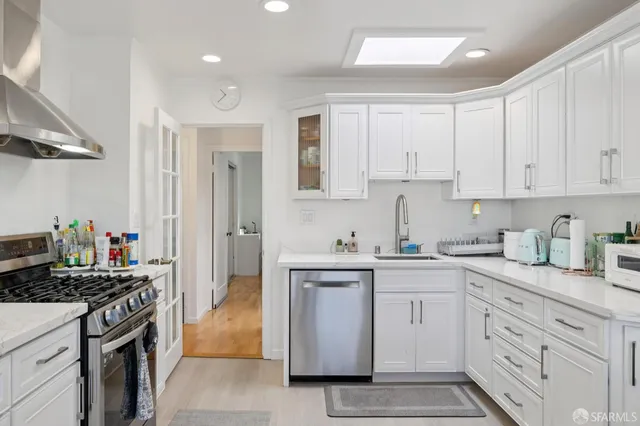 a kitchen with stainless steel appliances kitchen island granite countertop a sink a stove a refrigerator cabinets and a dining table