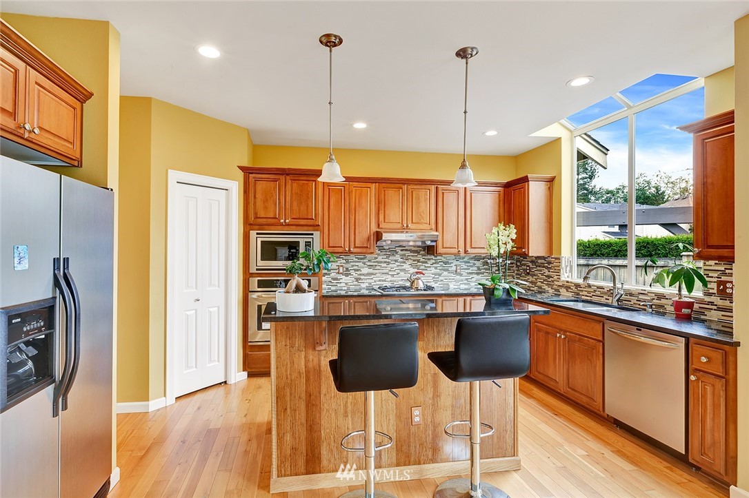 3617 156th Place Southeast Bothell, WA 98012 - Photo 4 of 18 a kitchen with stainless steel appliances kitchen island granite countertop a stove a refrigerator and a wooden cabinets