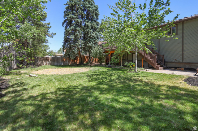 8938 Manchester Lane Sandy, UT 84093 - Photo 39 of 50 Expansive rear yard featuring green lawn, mature trees, a privacy fence, and a multi-level deck with wood stairs