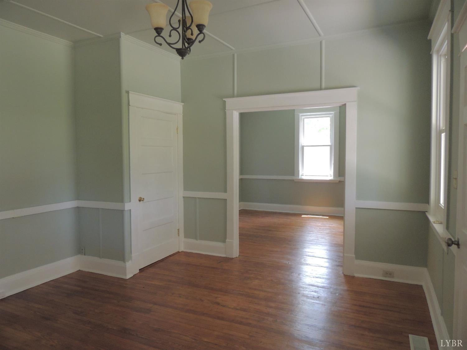 7007 Wards Road Rustburg, VA 24588 - Photo 13 of 26 an empty room with wooden floor chandelier and windows