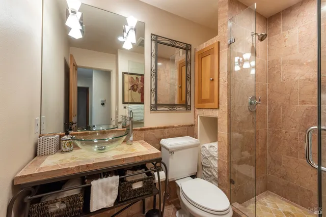 a bathroom with a granite countertop toilet sink shower and mirror