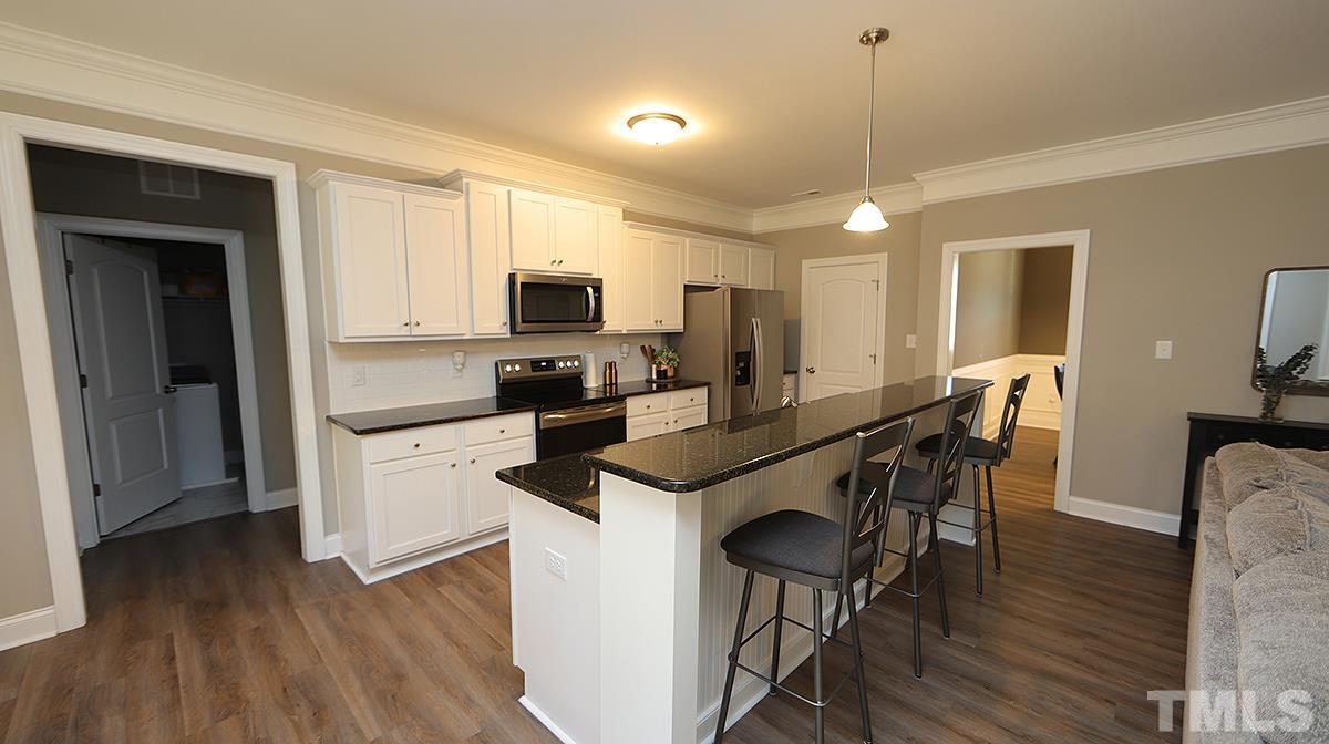 74 Flora Drive Benson, NC 27504 - Photo 11 of 33 a kitchen with kitchen island granite countertop wooden floors and white cabinets