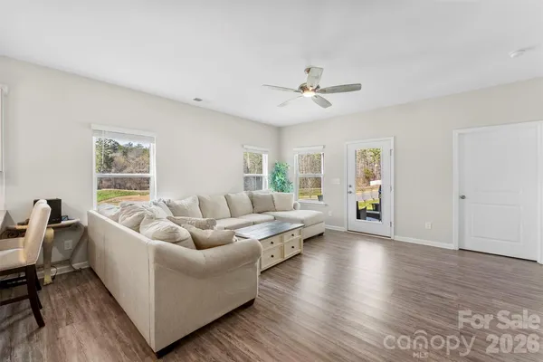 a living room with couches and a potted plant on a dresser with wooden floor