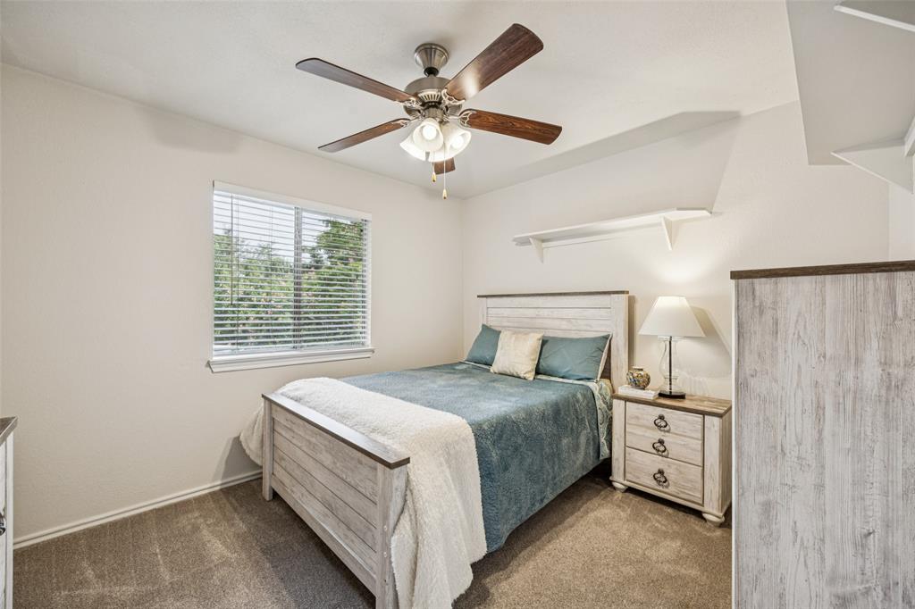 113 Windmill Ridge Drive Rockwall, TX 75032 - Photo 12 of 19 Secondary bedroom with plush carpet, ceiling fan, and a large window bringing in soft natural light.