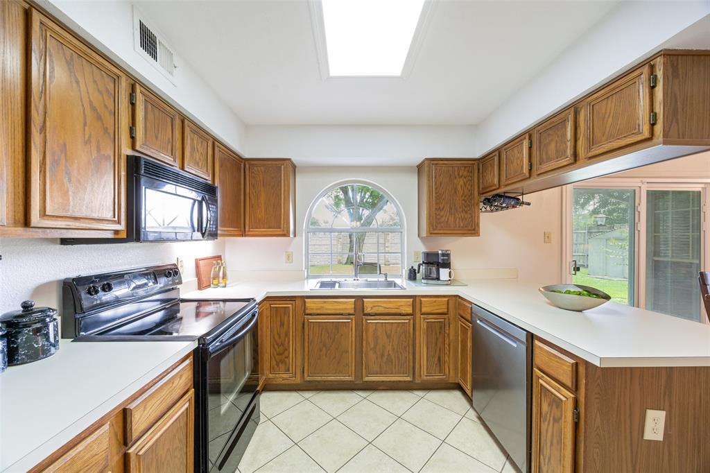 113 Windmill Ridge Drive Rockwall, TX 75032 - Photo 2 of 19 Bright kitchen with abundant cabinet storage, stainless steel appliances, and a charming arched window overlooking the backyard.