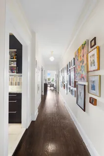 a view of a hallway with wooden floor and living room