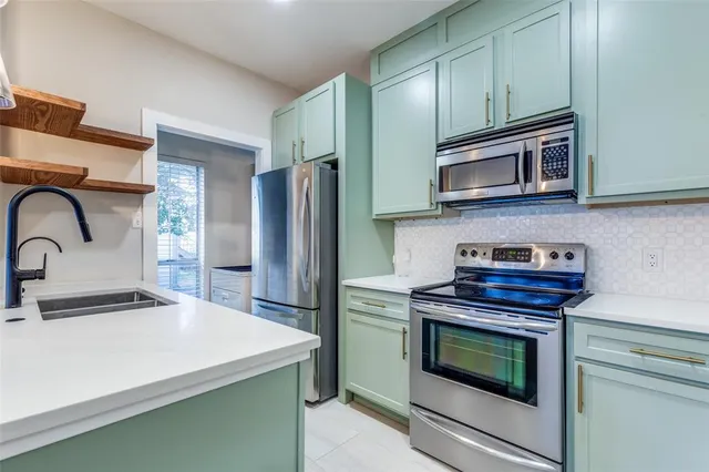 a kitchen with stainless steel appliances a stove microwave and sink