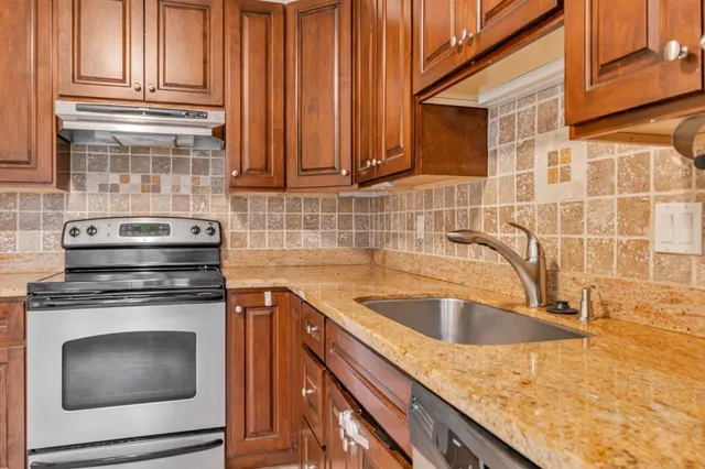 a kitchen with granite countertop a sink stove and cabinets