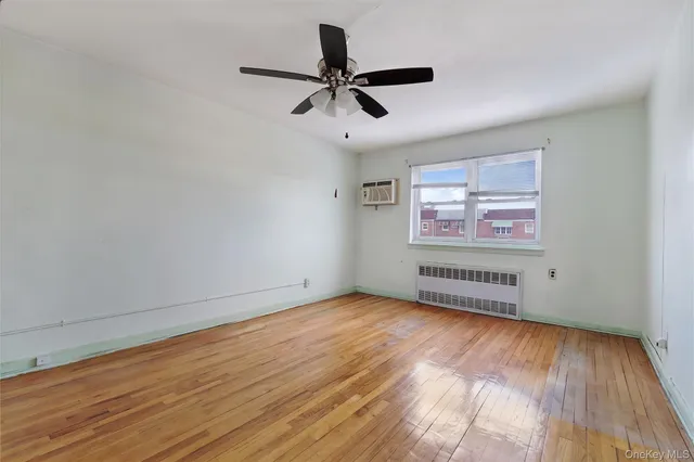 an empty room with wooden floor ceiling fan and windows