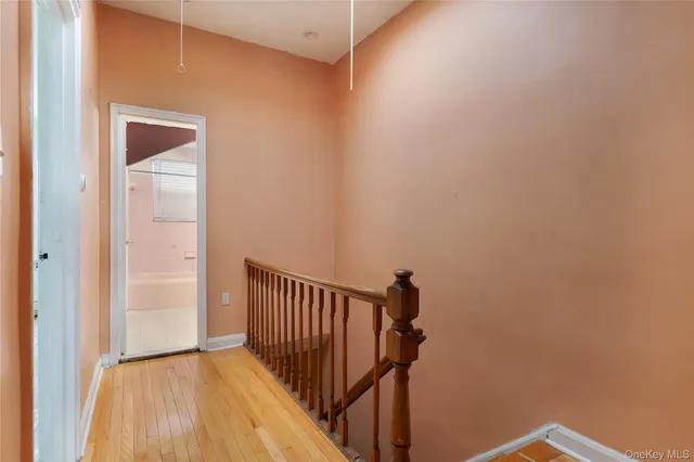 a view of a hallway with wooden floor and a bathroom