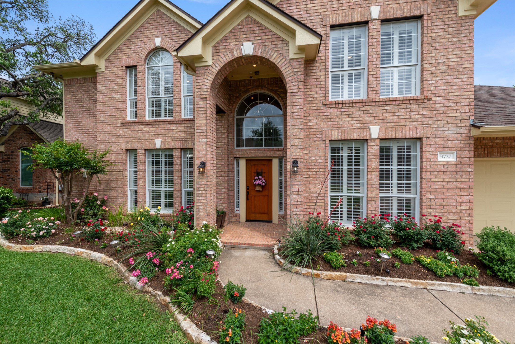 Lovely 2 story brick David Weekley home with arched covered entry and lushly landscaped