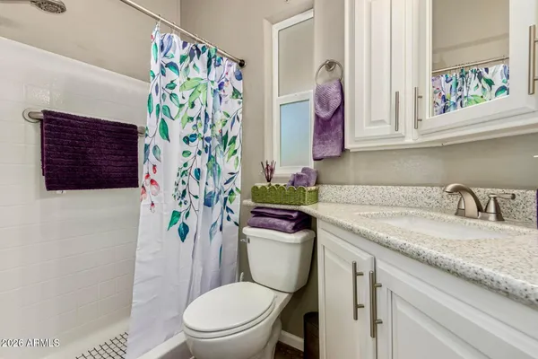 a bathroom with a granite countertop toilet sink and mirror