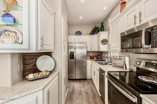 a kitchen with stainless steel appliances granite countertop a stove a sink dishwasher and a refrigerator with wooden floor