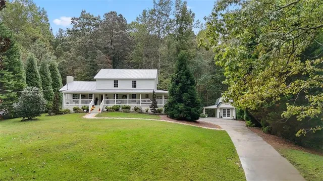 a view of a house with a big yard and large trees