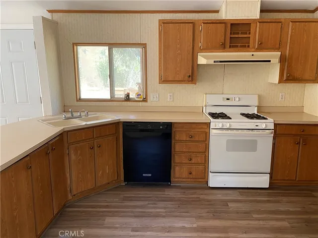 a kitchen with a stove white cabinets sink and dishwasher with wooden floor