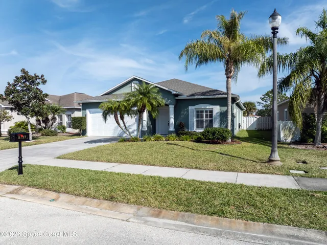 a front view of a house with a yard and palm trees