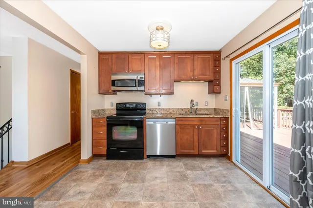a kitchen with granite countertop a stove a sink and a refrigerator
