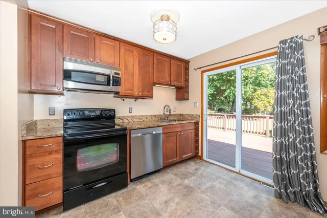 a kitchen with stainless steel appliances granite countertop a refrigerator a sink dishwasher and wooden cabinets with wooden floor