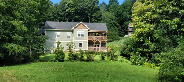 a kitchen with stainless steel appliances a sink a stove a refrigerator white cabinets and wooden floor