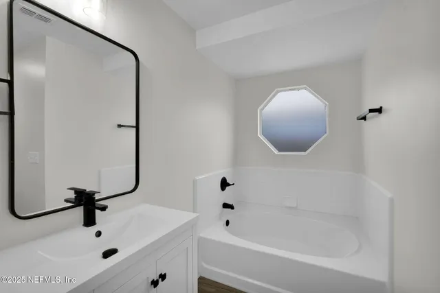 a bathroom with a tub sink and mirror