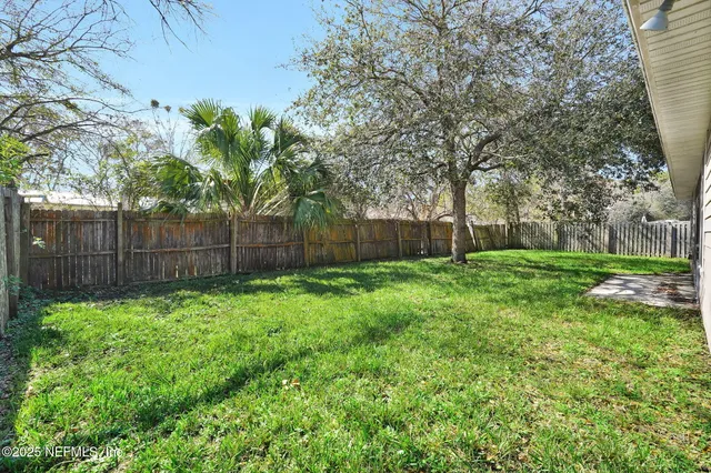 a view of a backyard with large trees and wooden fence