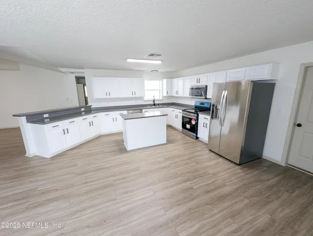 a kitchen with stainless steel appliances a refrigerator sink and microwave
