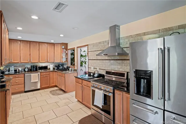 a kitchen with stainless steel appliances granite countertop a stove a sink and a refrigerator