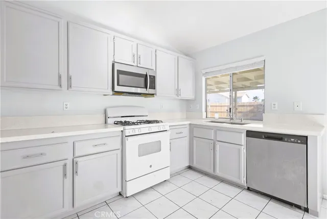 a kitchen with white cabinets appliances and a window