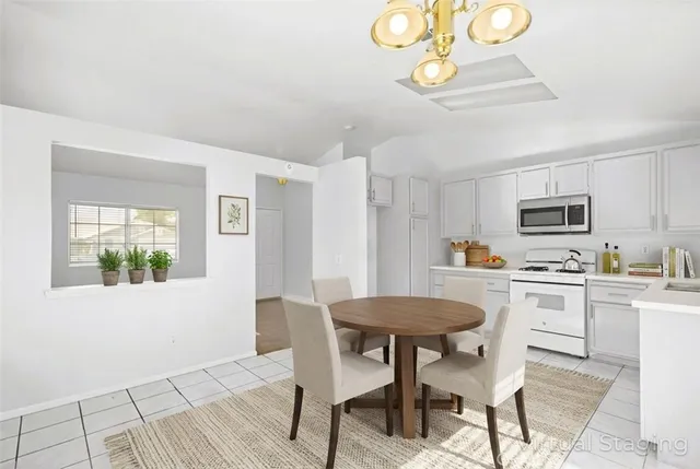 a kitchen with stainless steel appliances a stove a sink dishwasher a dining table and chairs with wooden floor