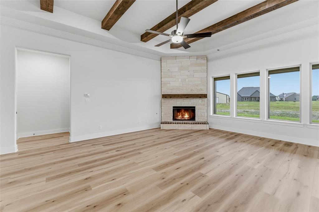 2208 Continent Court Krum, TX 76249 - Photo 12 of 26 Spacious room featuring wood-finish flooring and a stone-clad fireplace with a wood mantle