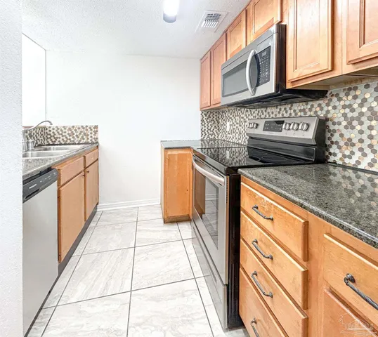 a kitchen with stainless steel appliances granite countertop a stove a sink and a microwave