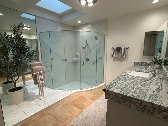 a bathroom with a granite countertop sink a toilet and shower