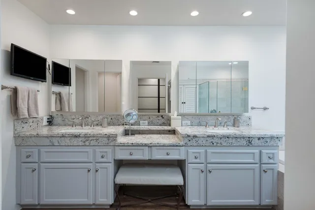 a spacious bathroom with a granite countertop sink a mirror and a shower