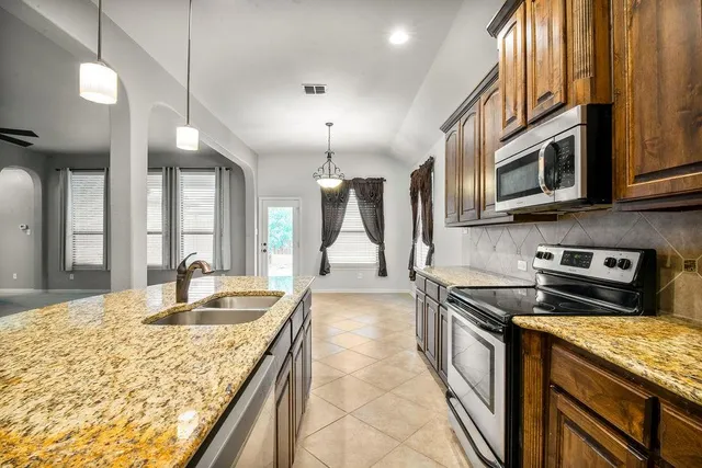 a kitchen with stainless steel appliances granite countertop a stove a sink and a microwave