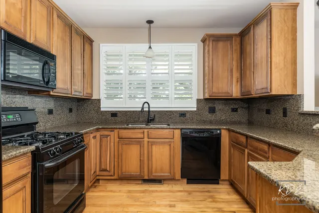 a kitchen with stainless steel appliances granite countertop wooden cabinets stove top oven and sink