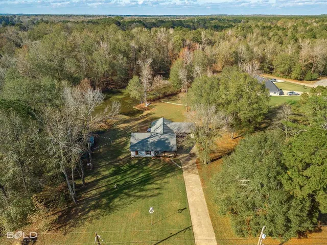 a view of a house with a big yard and large trees