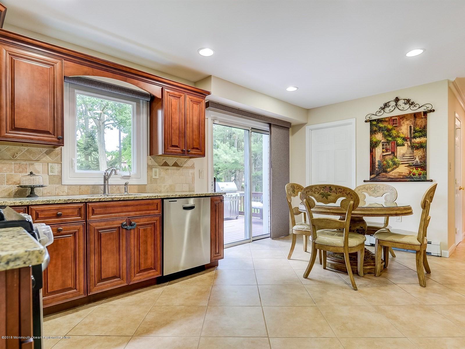 16 Canvasback Road Manalapan, NJ 07726 - Photo 11 of 26 a kitchen with stainless steel appliances granite countertop a table chairs and a refrigerator
