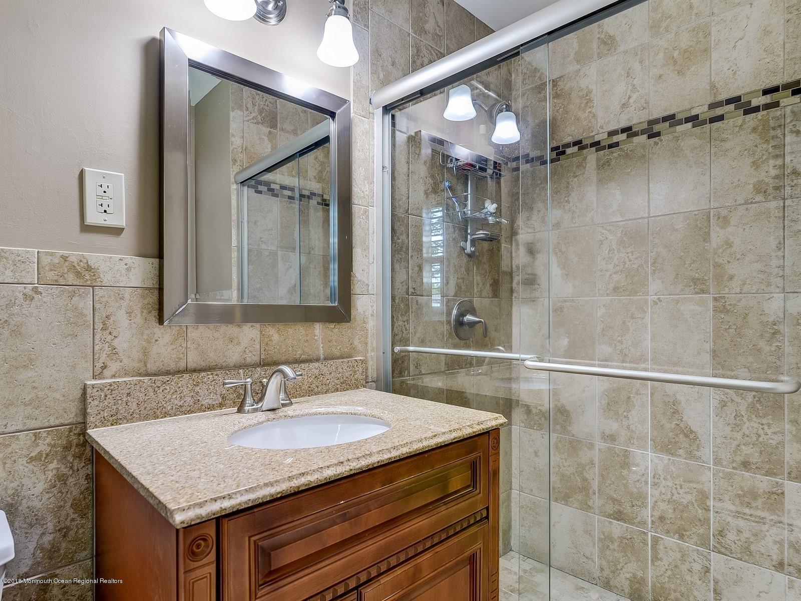 16 Canvasback Road Manalapan, NJ 07726 - Photo 17 of 26 a bathroom with a granite countertop sink a mirror and a shower
