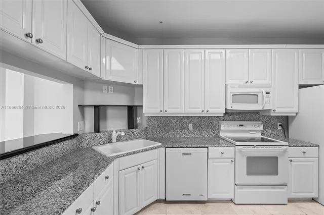 a kitchen with granite countertop a sink stainless steel appliances and white cabinets