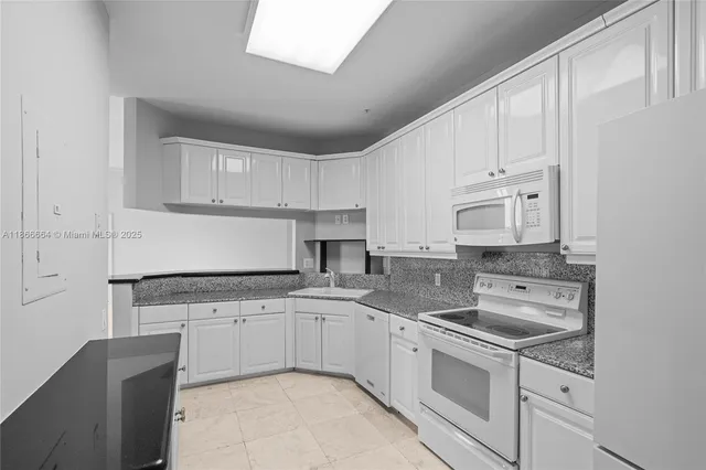 a kitchen with granite countertop white cabinets white stainless steel appliances with a sink and dishwasher