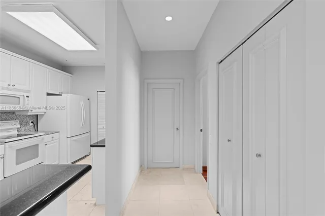 a view of a kitchen with white cabinets and refrigerator