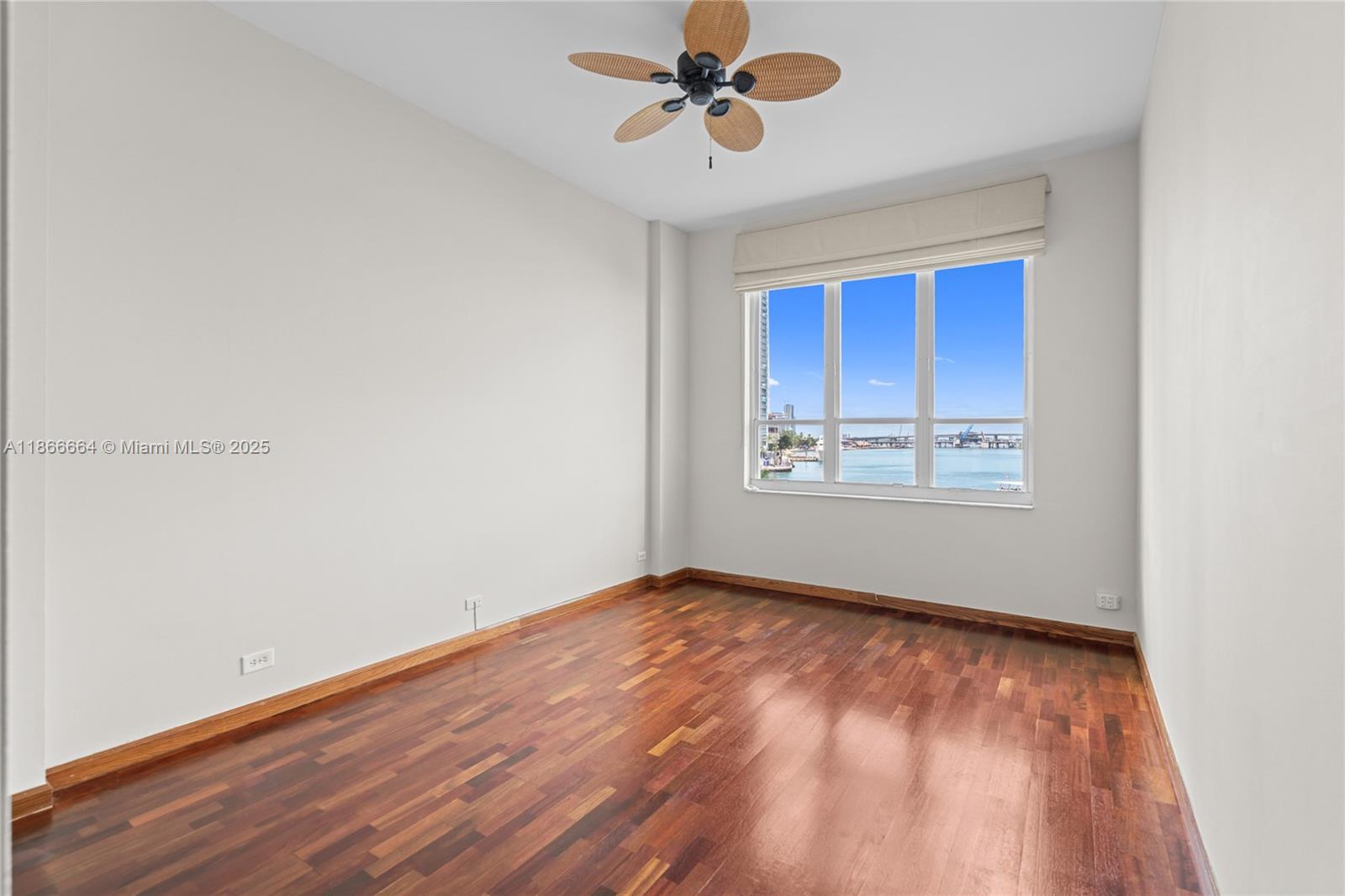 888 Brickell Key Drive, Unit 408 Miami, FL 33131 - Photo 41 of 54 an empty room with wooden floor chandelier fan and windows
