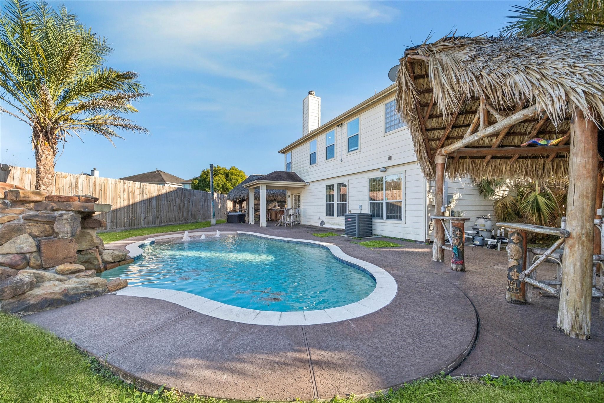 Another view of the backyard oasis showcasing the pool, expansive patio space, and multiple outdoor entertaining areas.