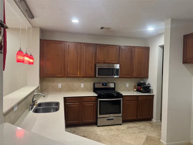 an empty room with wooden floor and way to kitchen