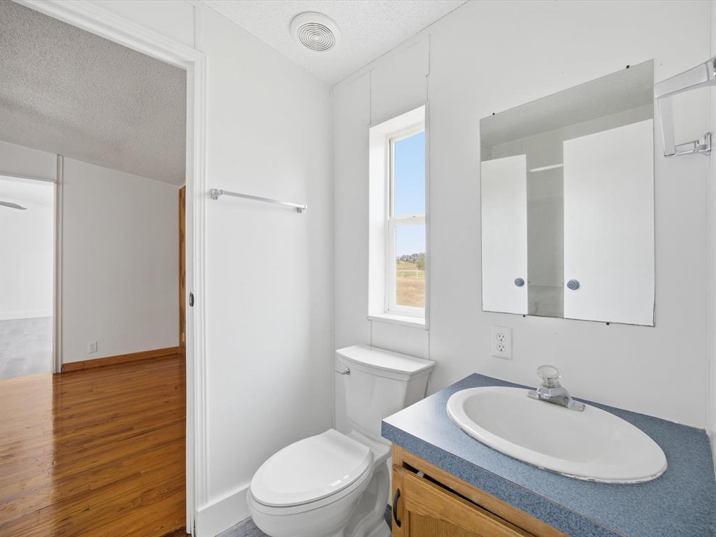 229 Morgan Road Italy, TX 76651 - Photo 26 of 40 a bathroom with a granite countertop sink a toilet a mirror and shower