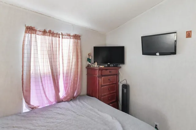 a bedroom with a flat screen tv and a window