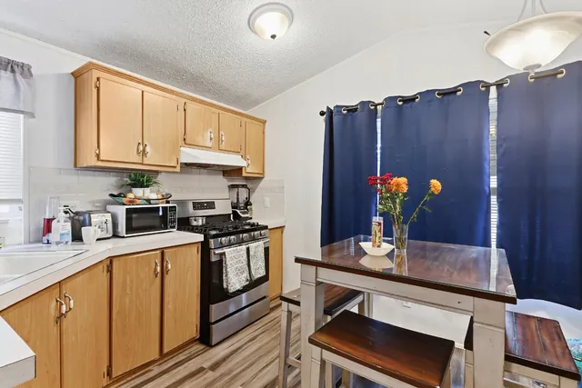 a kitchen with stainless steel appliances kitchen island granite countertop a table chairs in it and wooden floors