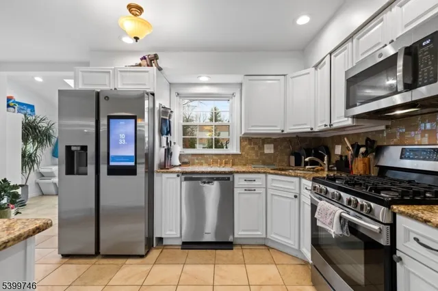 a kitchen with stainless steel appliances granite countertop a refrigerator a stove top oven and sink