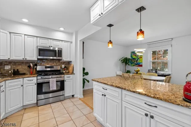 a kitchen with granite countertop a sink stainless steel appliances and white cabinets